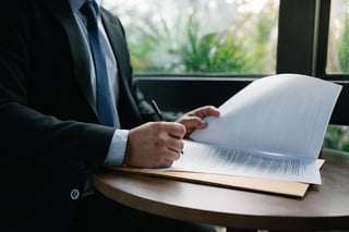 Businessman signing a document on a round table, showcasing legal agreement and professional commitment.